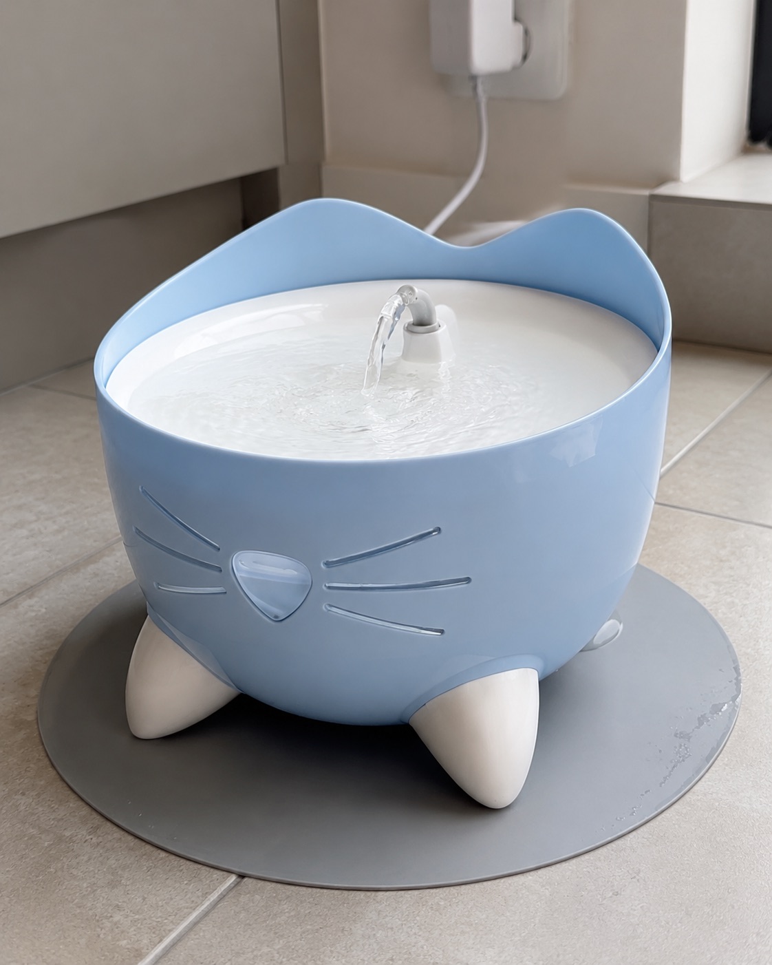 Catit Pixi blue pet fountain running with visible water flow and power connection